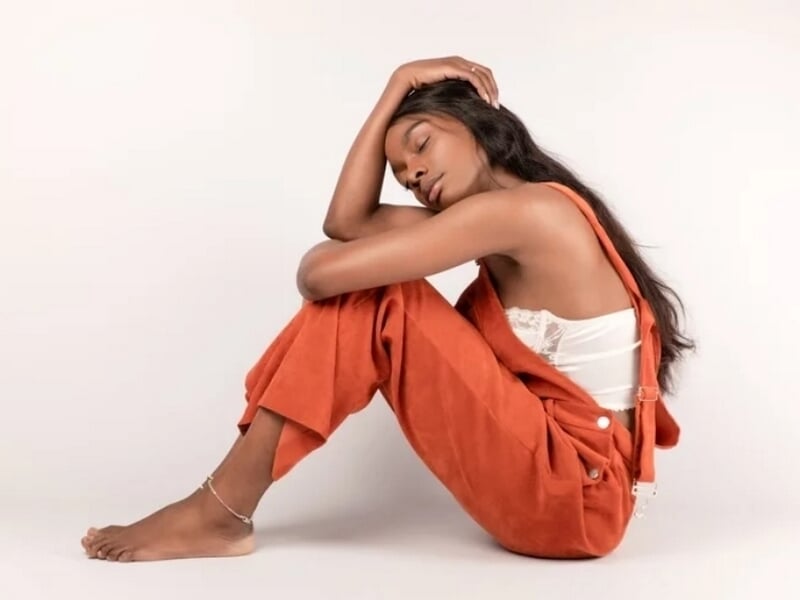 Jeune femme assise au sol, habillée en pantalon orange et haut blanc, lors d'un shooting lifestyle à Besançon.