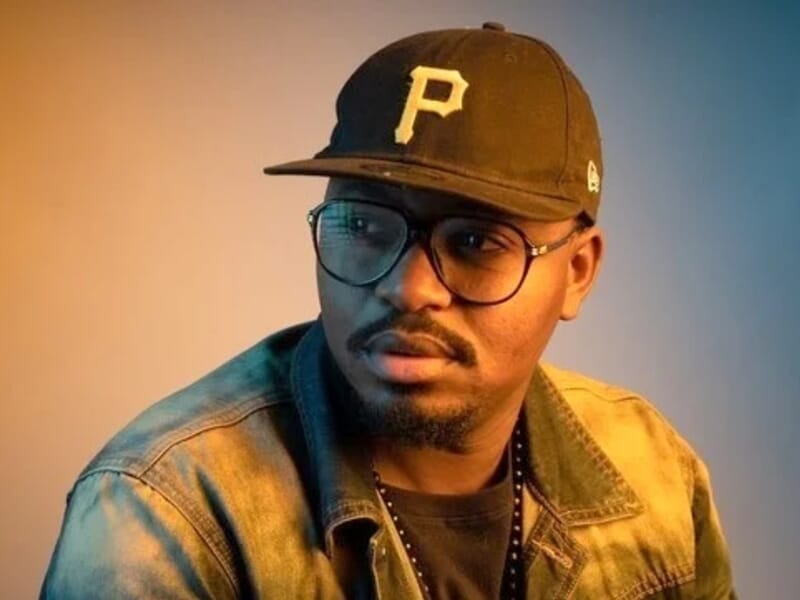 Homme portant une casquette noire et des lunettes, vêtu d'une veste en jean lors d'un shooting photo portrait à Besançon.