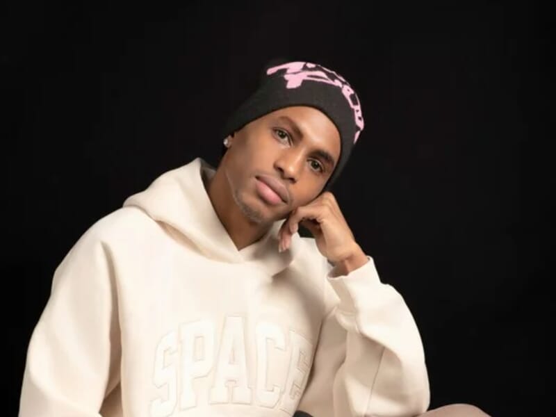 Jeune homme en sweat à capuche blanc et bonnet noir avec motif rose, lors d'un shooting photo portrait à Besançon.