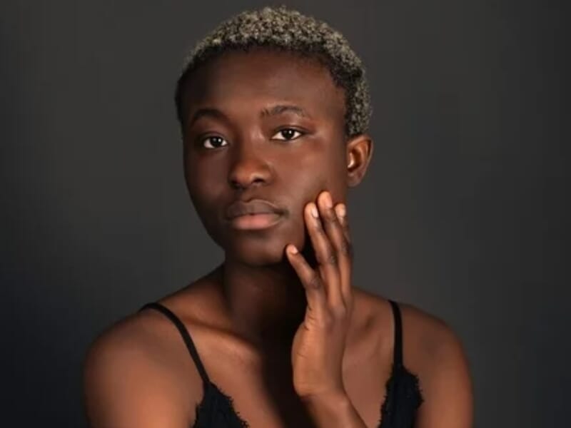 Portrait d'une femme aux cheveux courts et bouclés, posant avec la main sur la joue lors d'un shooting photo portrait à Besançon.