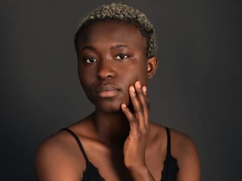 Portrait d'une femme aux cheveux courts et bouclés, posant avec la main sur la joue lors d'un shooting photo portrait à Besançon.