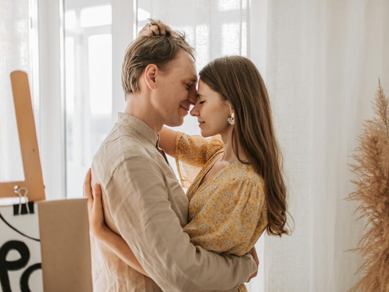 Un couple s'enlaçant tendrement dans une pièce lumineuse lors d'un shooting photo couple à Besançon.