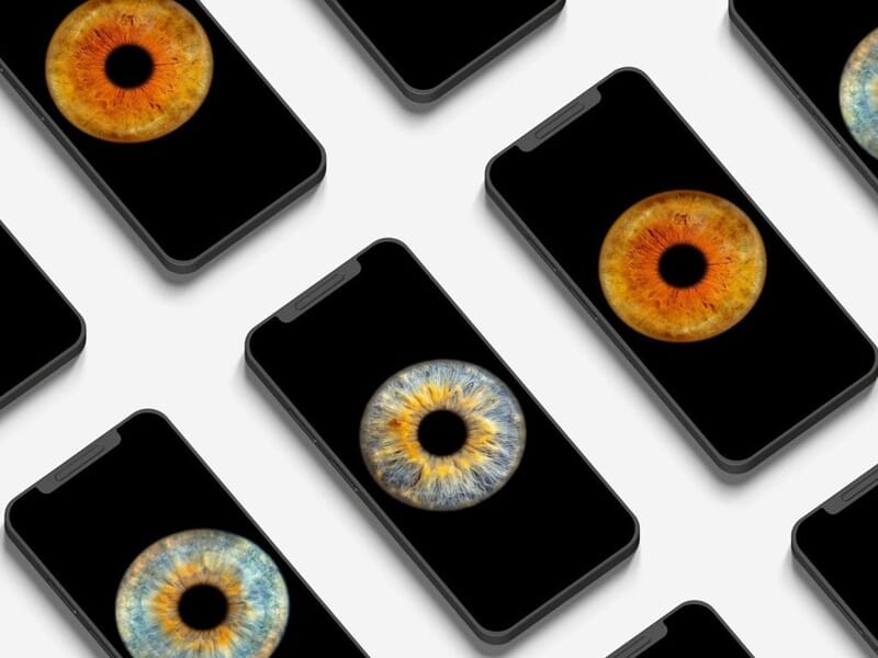 Plusieurs smartphones noirs affichant des images d'iris d'yeux colorés sur fond noir, alignés en diagonale.