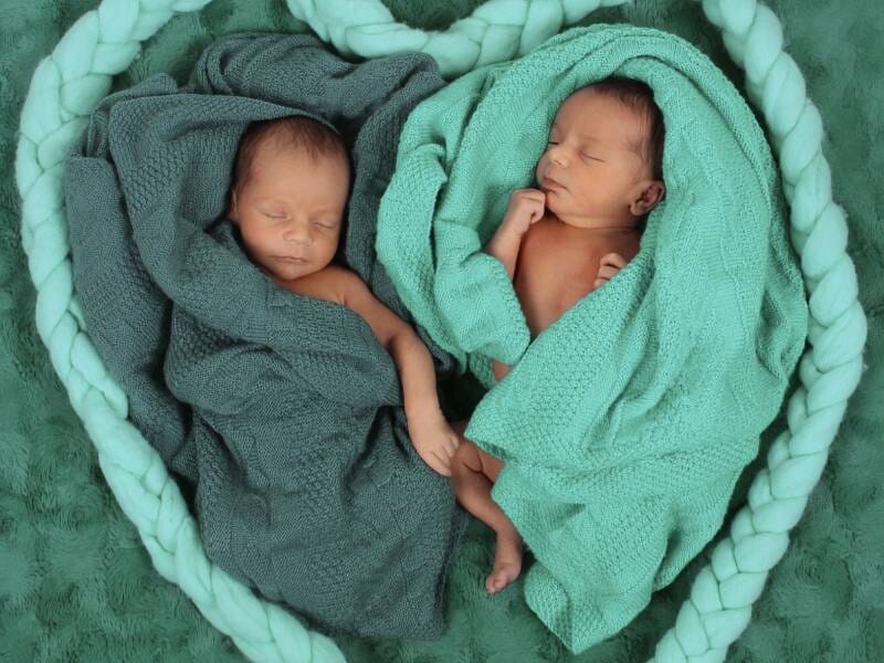 Deux bébés endormis enveloppés dans des couvertures vertes, formant un cœur avec une grosse corde tressée, lors d'un shooting près d'Arles.