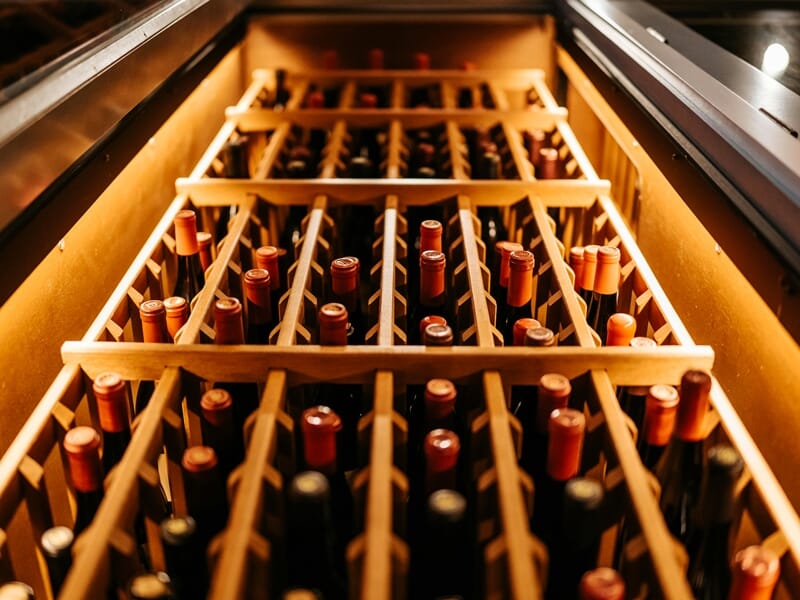 Cave à vin avec plusieurs bouteilles rangées dans des casiers en bois, éclairage chaleureux et ambiance cosy.