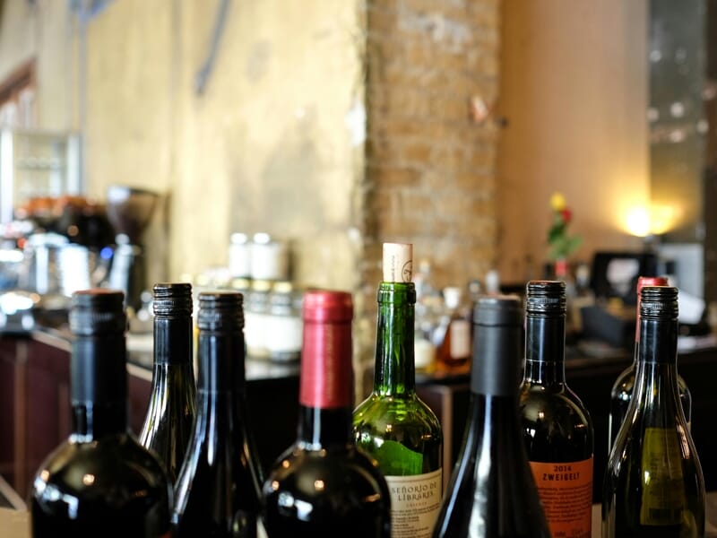 Bouteilles de vin alignées sur un comptoir dans un bar ou restaurant avec un mur en pierre en arrière-plan flou.