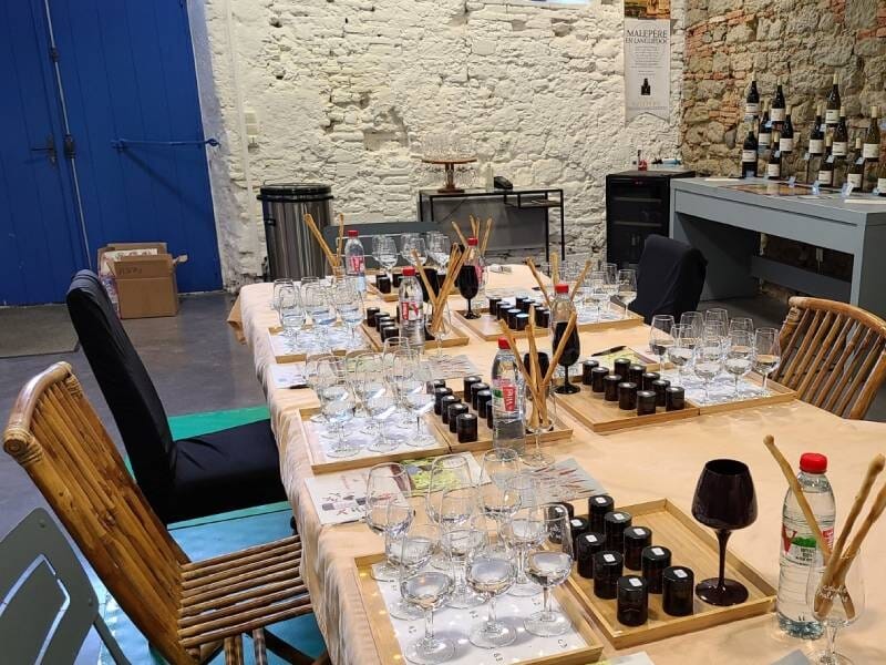 Table en bois avec verres à vin, bouteilles et accessoires disposés pour une séance de dégustation dans une cave, près de Carcassonne.