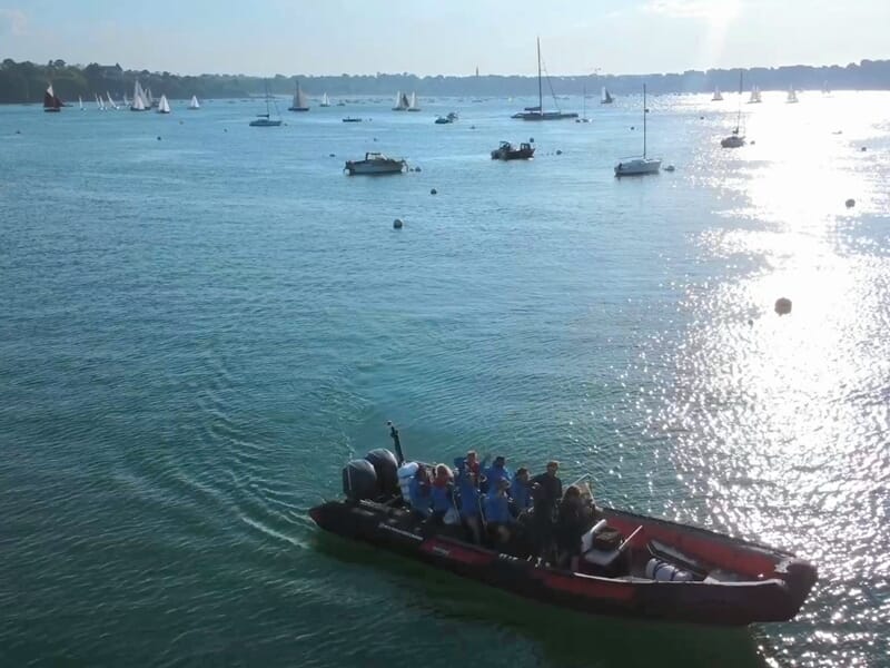 Un bateau pneumatique avec plusieurs passagers navigue sur une mer calme lors d'une balade en bateau à Saint-Malo. 