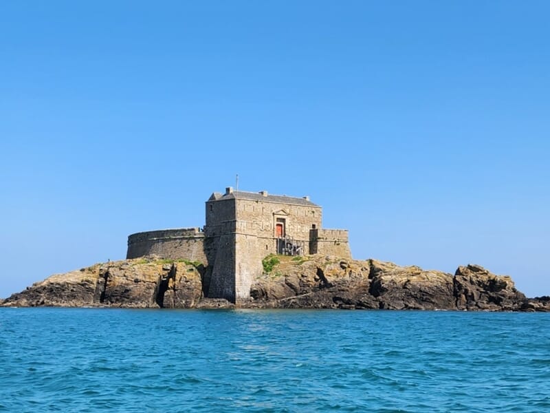Un fort en pierre sur un îlot rocheux entouré d'eau bleue lors d'une balade en bateau à Saint-Malo. 