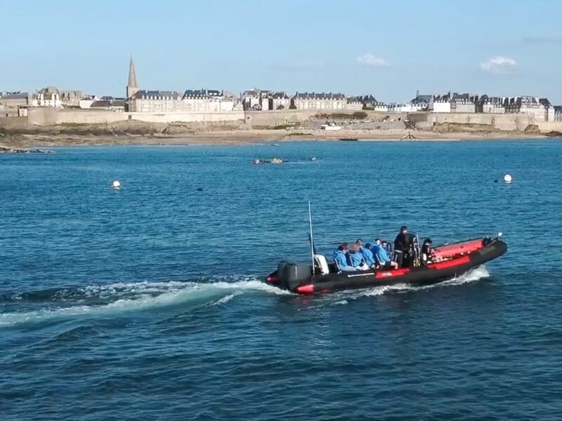 Un bateau pneumatique avec plusieurs passagers navigue sur une mer calme lors d'une balade en bateau à Saint-Malo. 