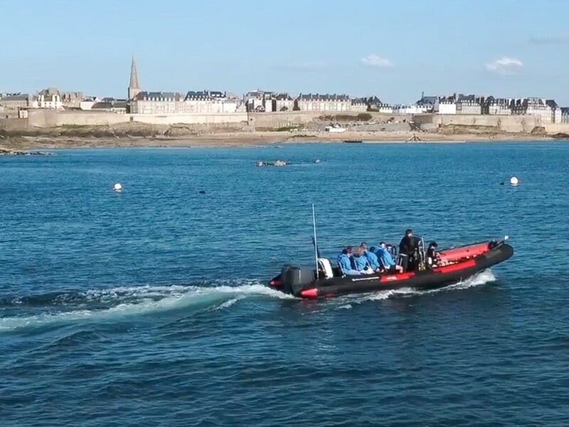 Un bateau pneumatique avec plusieurs passagers navigue sur une mer calme lors d'une balade en bateau à Saint-Malo. 