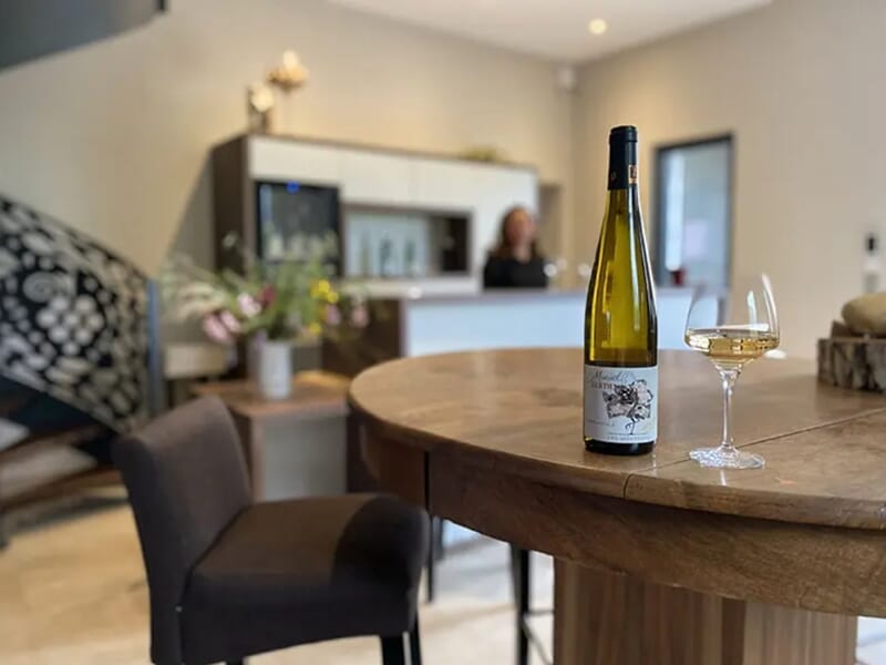 Bouteille de vin blanc et verre posés sur une table lors d'un week-end oenologie près de Colmar.