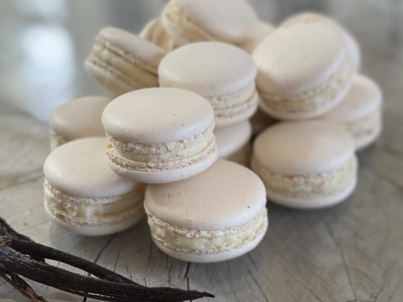 Gros plan sur plusieurs macarons blancs posés sur une surface en bois lors d'un cours de pâtisserie à Lille.