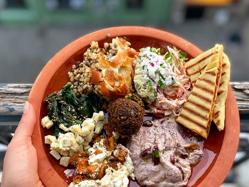 Un plat végétarien coloré avec falafel, légumes, pain pita grillé et différentes sauces servies réalisé lors d'un cours de cuisine à Lille.
