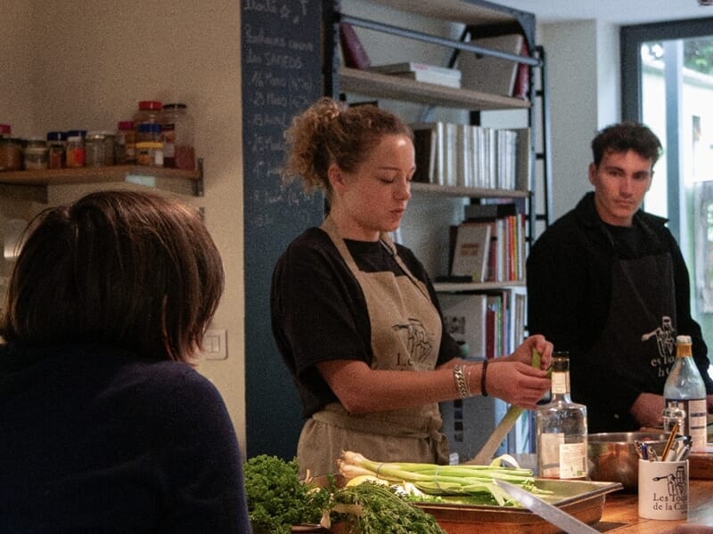 Un cours de cuisine à Lille en intérieur avec une femme et un homme concentrés sur la préparation d'ingrédients frais.