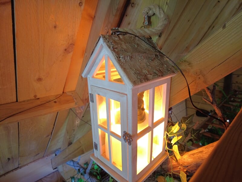 Lanterne blanche en bois éclairée, suspendue dans un coin en bois lors d'une nuit cabane près de Saint-Nazaire.