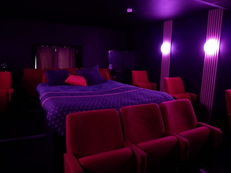 Chambre sombre avec lit double, couverture à motifs, lors d'une nuit en Love Room près de Châteauroux.