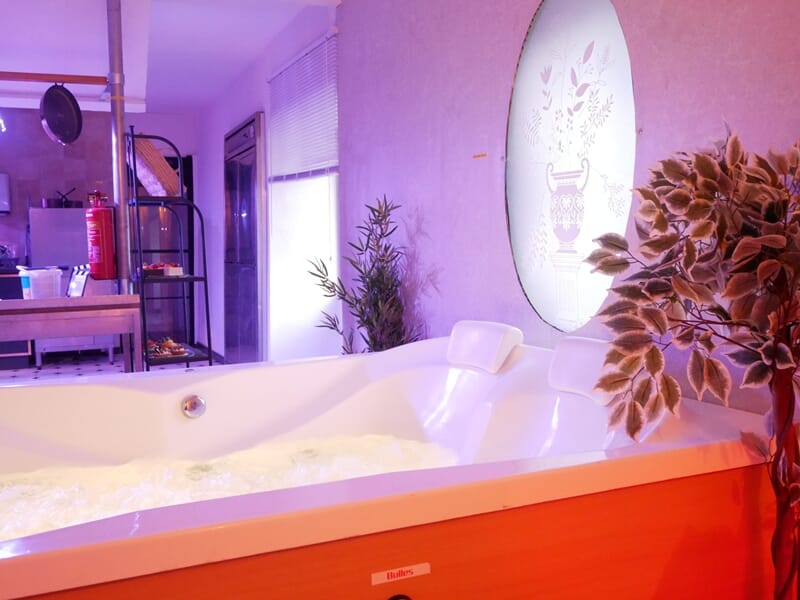 Baignoire jacuzzi blanche en fonctionnement avec mousse, lors d'une nuit en Love Room près de Châteauroux.