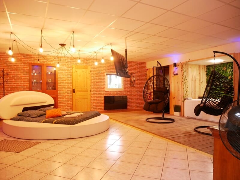 Chambre spacieuse avec lit rond, murs en briques, lors d'une nuit en Love Room près de Bourges.