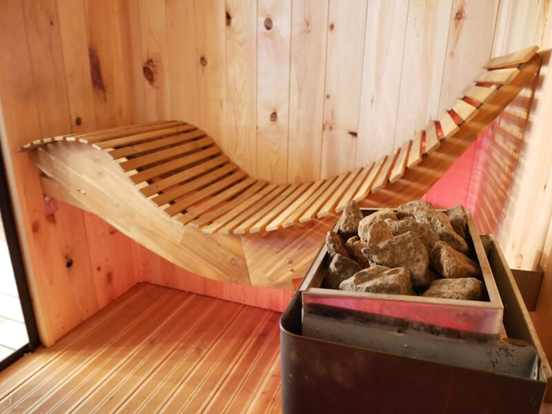 Sauna en bois avec banc ergonomique et pierres chauffantes lors d'une nuit en Love Room près de Bourges.