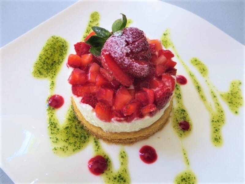Dessert élégant avec base biscuitée, crème blanche, fraises fraîches lors d'un cours de pâtisserie à Nice.