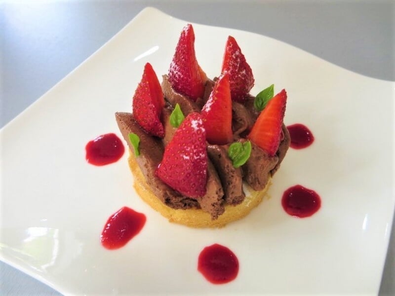 Dessert raffiné avec base biscuitée, mousse au chocolat, fraises entières lors d'un cours de pâtisserie à Nice.