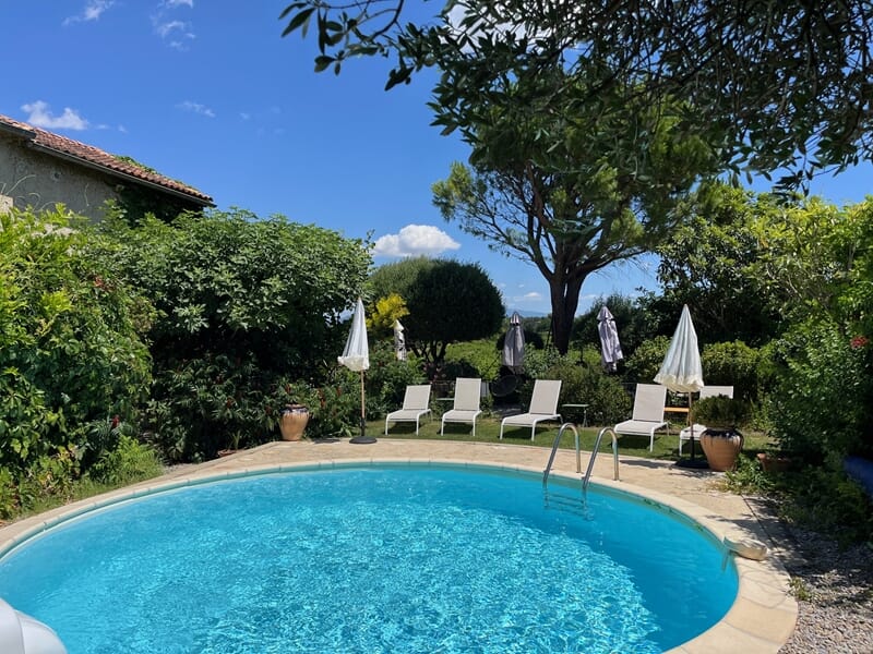 Piscine ronde entourée de chaises longues blanches lors d'un week-end oenologie près de Châteauneuf-du-Pape.