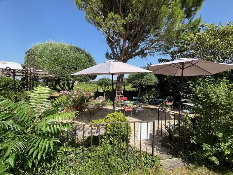 Jardin avec des parasols blancs, des chaises et une table lors d'un week-end oenologie près de Châteauneuf-du-Pape.