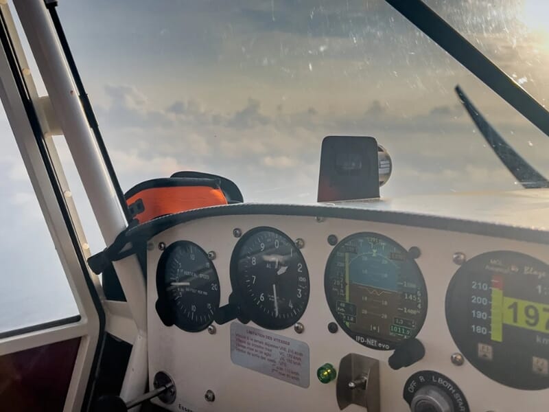 Vue du tableau de bord d'un avion ULM en vol avec le ciel et les nuages visibles lors d'une initiation au pilotage d'un avion ULM près de Toulon. 