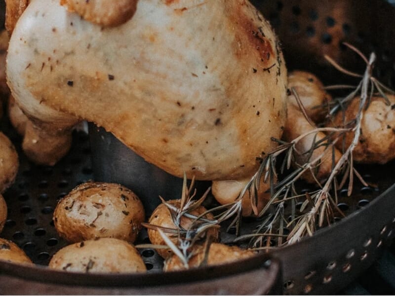 Poulet rôti entouré de petites pommes de terre et de branches de romarin lors d'un atelier de cuisine barbecue à Brest.