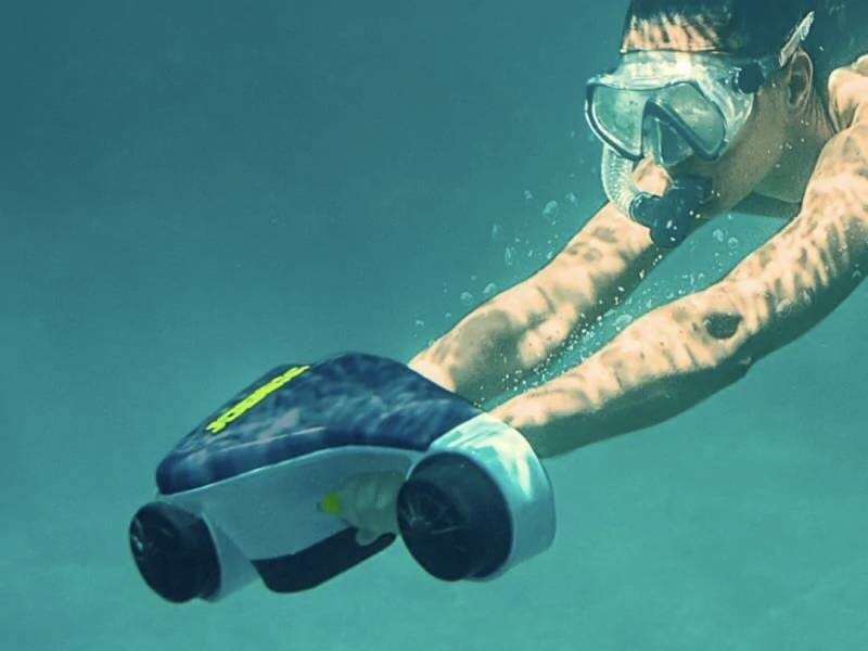 Personne sous l'eau utilisant un scooter de plongée électrique pour explorer les fonds marins clairs et bleus.