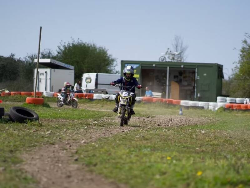 Jeune pilote en moto tout-terrain sur piste de terre lors d'un stage de pilotage moto en plein air.