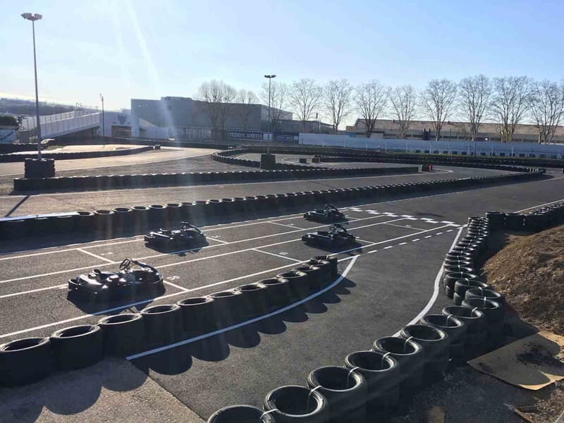 Vue de la piste de karting d'Albi avec plusieurs karts en course entourés de barrières en pneus.