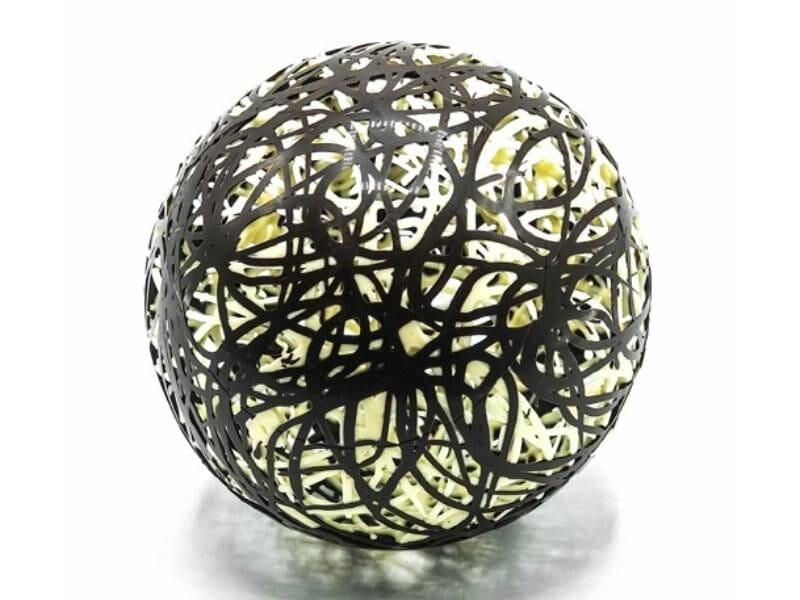 Sphère décorative en chocolat noir et blanc avec motifs entrelacés, posée sur fond blanc.