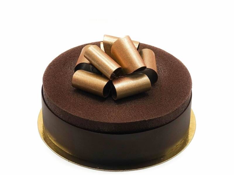 Gâteau rond au chocolat avec décoration en rubans dorés et noirs, posé sur un support doré.
