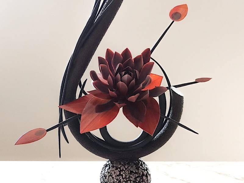 Sculpture artistique en chocolat noir et rouge représentant une fleur stylisée avec des pétales et des tiges délicates, réalisée lors d'un cours de création en chocolat près du Havre.