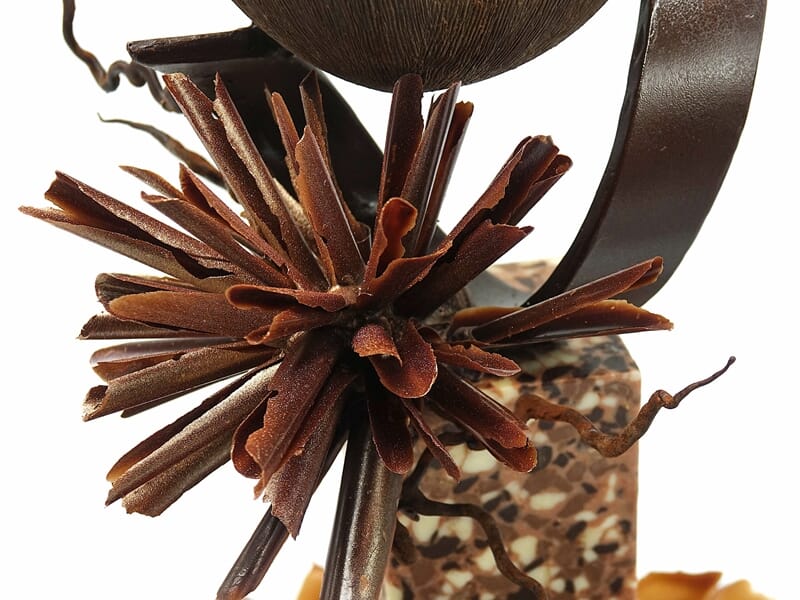 Sculpture artistique en métal avec des éléments en forme de pétales et des détails complexes en arrière-plan.