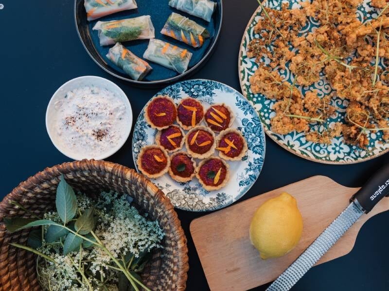 Assortiment de plats frais avec rouleaux de printemps, beignets croustillants et petites bouchées colorées sur table bleue, préparés lors d'un cours de cuisine à Rennes.
