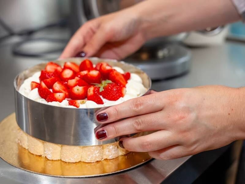 Gros plan sur un gâteau décoré de fraises fraîches et de crème, posé sur un plan de travail en cuisine lors d'un atelier pâtisserie à Montpellier.