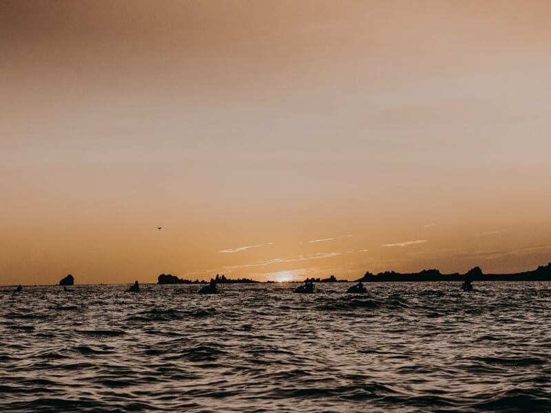 Coucher de soleil sur la mer avec des rochers sombres lors d'une randonnée en jet-ski au port d'Ajaccio.