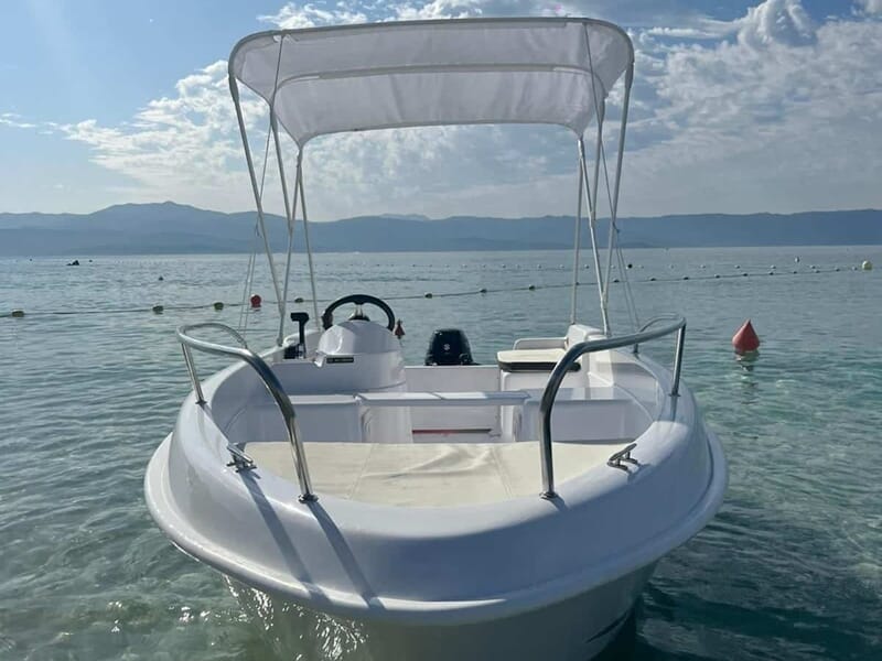 Petit bateau blanc avec un auvent, flottant sur une eau claire lors d'une location de bateau à Ajaccio. 