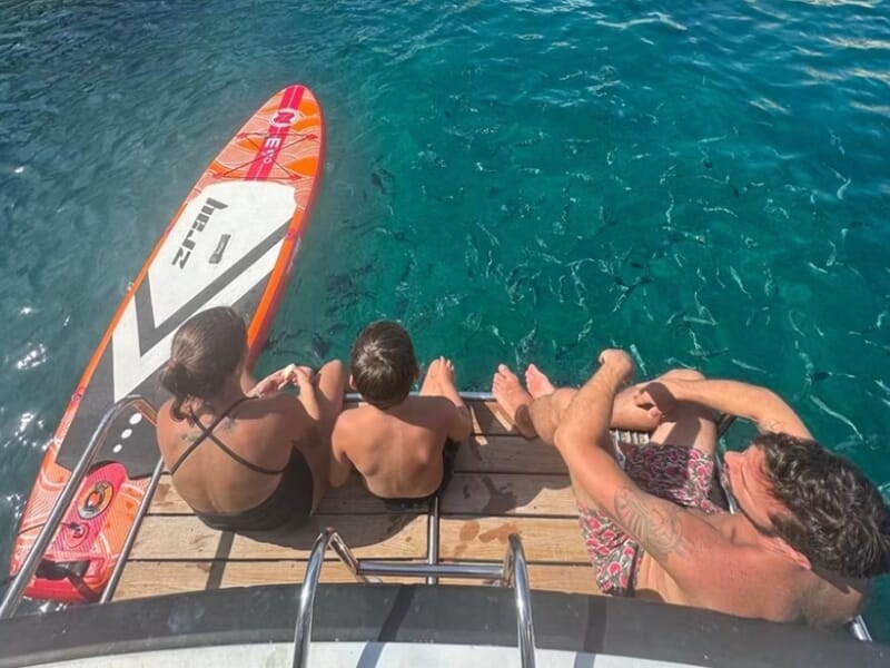 Trois personnes assises sur le bord d'un bateau, lors d'une balade en bateau à Marseille. 