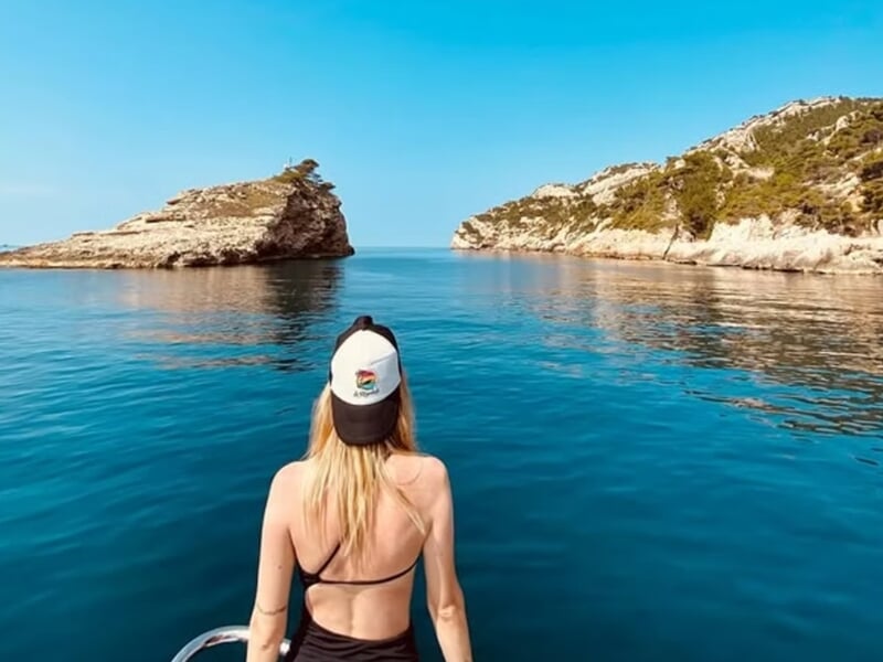Femme vue de dos sur un bateau regardant une mer calme lors d'une balade en bateau à Marseille.