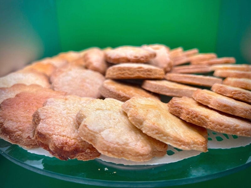 Assortiment de biscuits dorés et croustillants disposés en cercle sur un plateau vert.