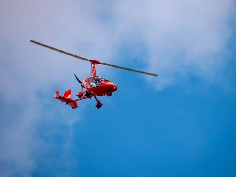 ULM rouge dans un ciel bleu avec quelques nuages, capturé en plein vol lors d'un baptême près de Blois.