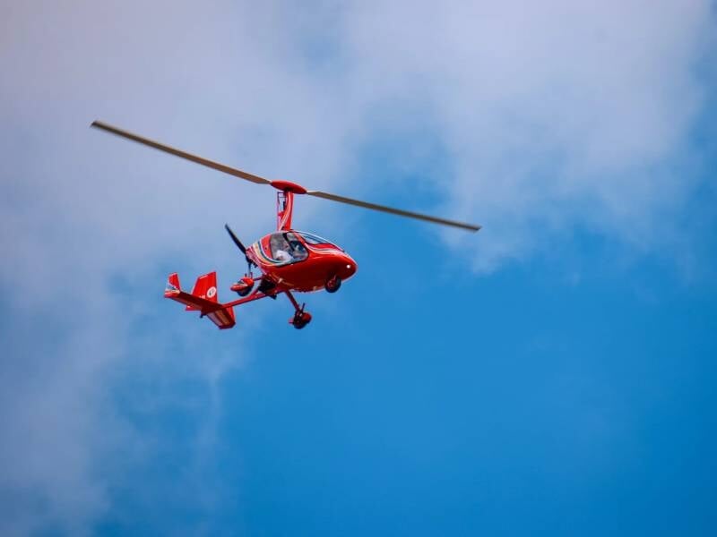 ULM rouge dans un ciel bleu avec quelques nuages, capturé en plein vol lors d'un baptême près de Blois.