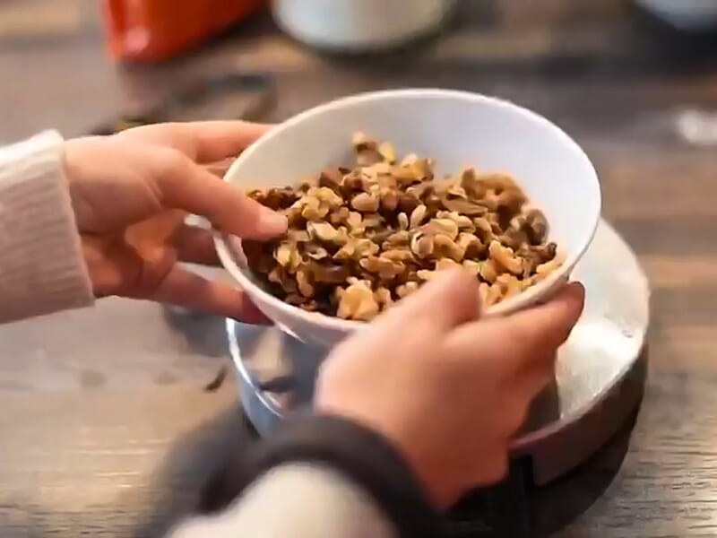 Mains tenant un bol rempli de noix, prêtes à être utilisées pour une recette de cuisine.