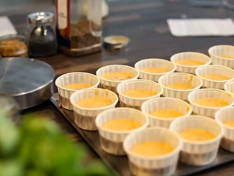 Plusieurs petits moules remplis d'une préparation orange posés sur une table dans une cuisine.