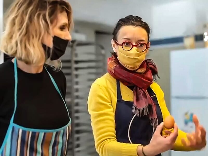 Deux femmes en tablier et masque discutant dans une cuisine pendant un atelier de cuisine à Castelnau-le-Lez.