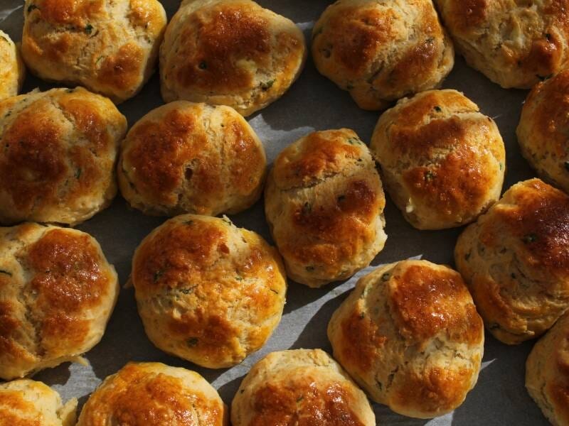 Petits pains dorés au four, disposés en rangées serrées sur une plaque de cuisson, prêts à être dégustés.